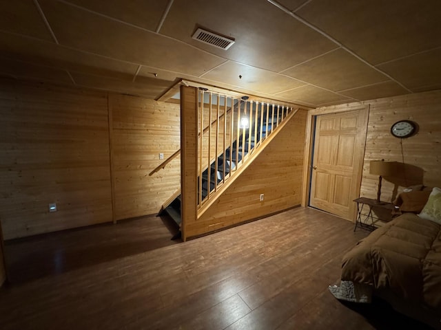 finished below grade area with stairs, visible vents, wood walls, and hardwood / wood-style flooring