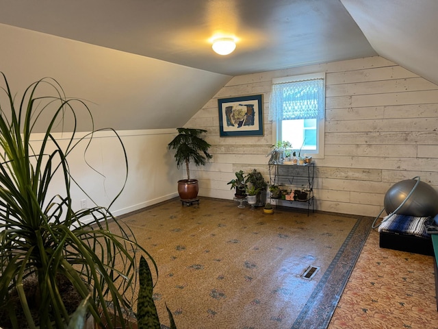 bonus room with vaulted ceiling, wooden walls, visible vents, and baseboards