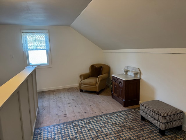 living area with light wood-style flooring, baseboards, and vaulted ceiling