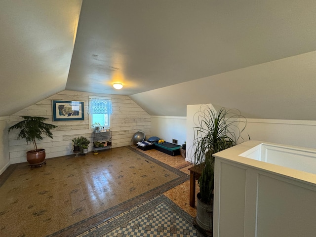 bonus room with vaulted ceiling and wood walls