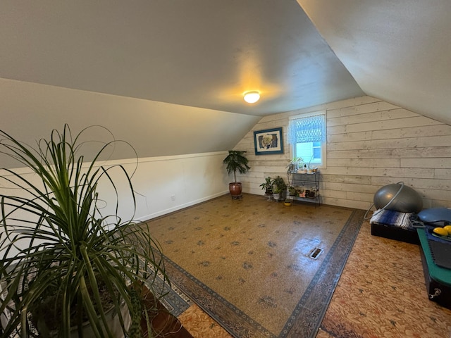 additional living space featuring lofted ceiling and wood walls