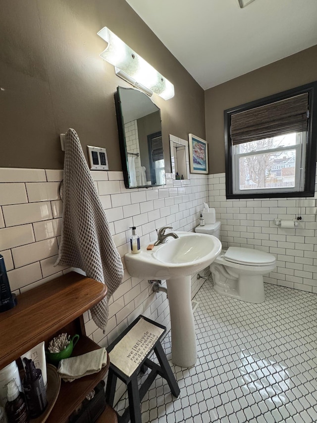 half bath with wainscoting, toilet, and tile walls