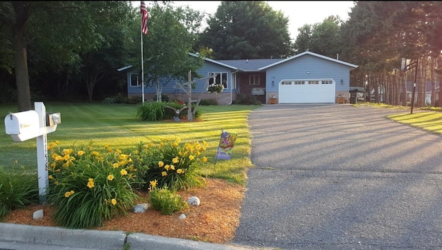 single story home featuring a garage, driveway, and a front lawn