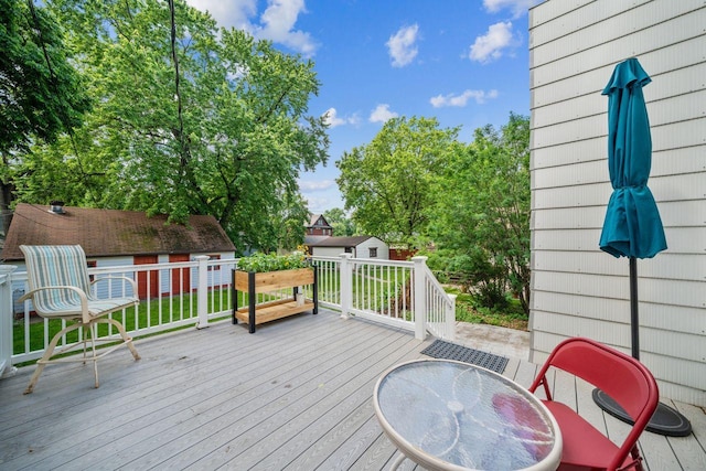 wooden terrace with an outbuilding and a lawn