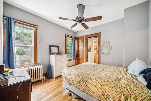 bedroom featuring light wood-style flooring, radiator, and a ceiling fan