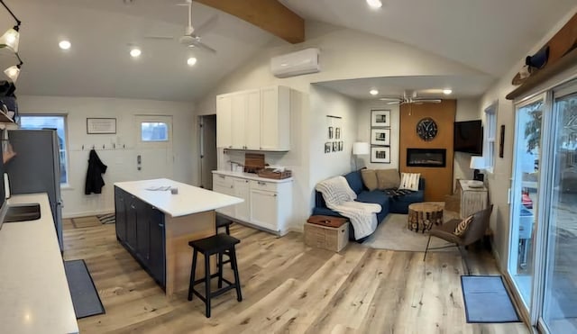 kitchen with white cabinetry, vaulted ceiling with beams, ceiling fan, and a wall unit AC