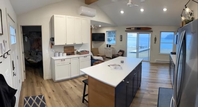 kitchen featuring a center island, lofted ceiling, freestanding refrigerator, light wood-style floors, and white cabinetry