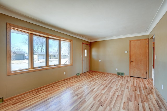 unfurnished room featuring light wood-type flooring, visible vents, and ornamental molding