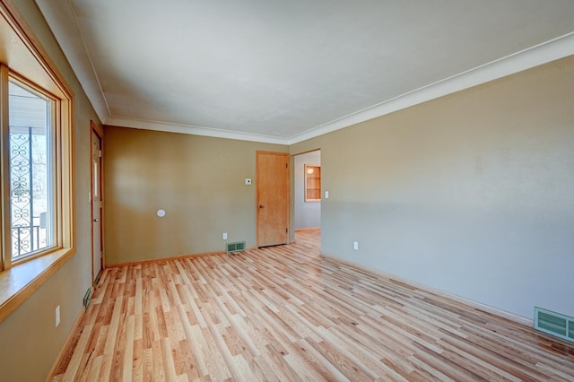 unfurnished room featuring light wood-type flooring, visible vents, and crown molding