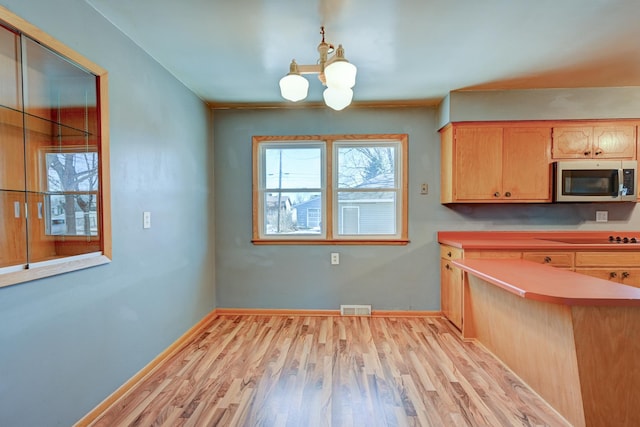 kitchen with a chandelier, black electric stovetop, visible vents, light wood-type flooring, and stainless steel microwave