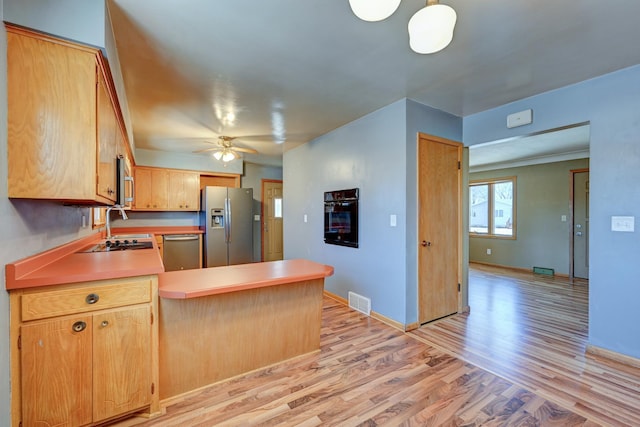 kitchen featuring stainless steel appliances, a peninsula, visible vents, light wood-style floors, and light countertops