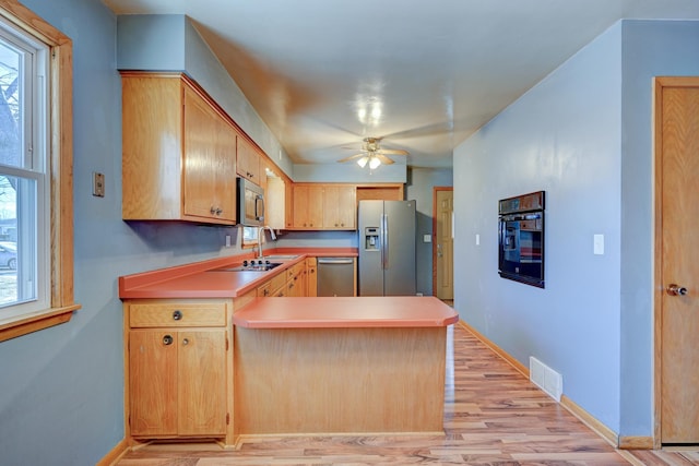 kitchen with light wood-style flooring, stainless steel appliances, a peninsula, visible vents, and baseboards