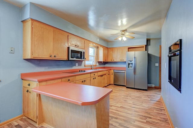 kitchen featuring light wood-type flooring, a sink, a peninsula, and black appliances