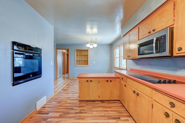 kitchen with visible vents, light wood-style flooring, an inviting chandelier, a peninsula, and black appliances