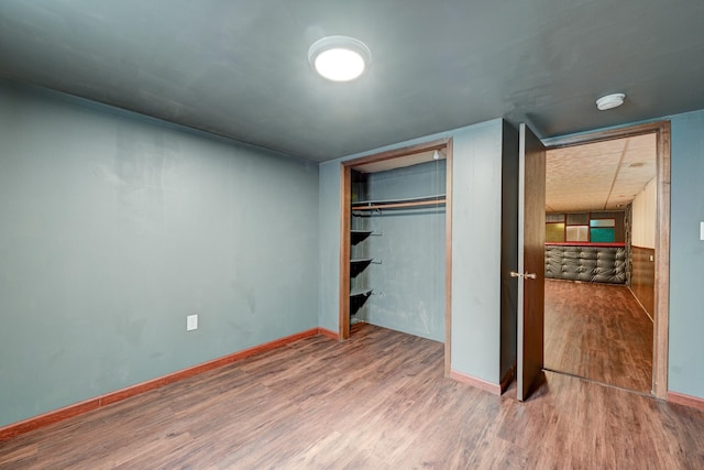 unfurnished bedroom with a closet, wood finished floors, and baseboards