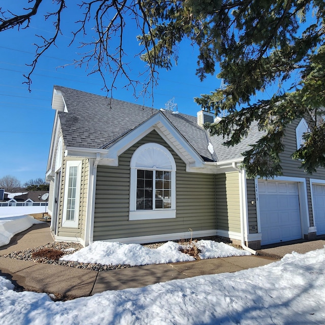 view of snow covered exterior featuring a shingled roof and a chimney