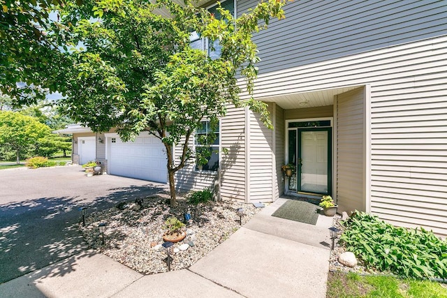 view of exterior entry with driveway and a garage