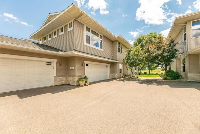 view of front of home with stone siding, driveway, and a garage