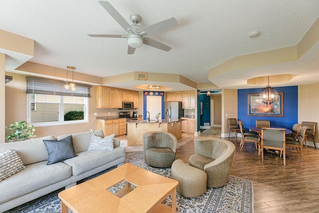 living area with a textured ceiling, baseboards, and light wood-style floors