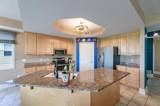 kitchen featuring a tray ceiling, an inviting chandelier, a sink, light brown cabinetry, and appliances with stainless steel finishes