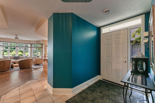 entryway with tile patterned flooring, a textured ceiling, baseboards, and a ceiling fan