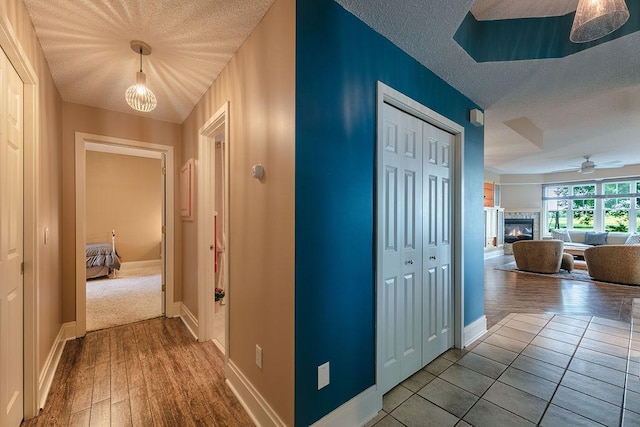 hallway featuring wood finished floors, baseboards, and a textured ceiling