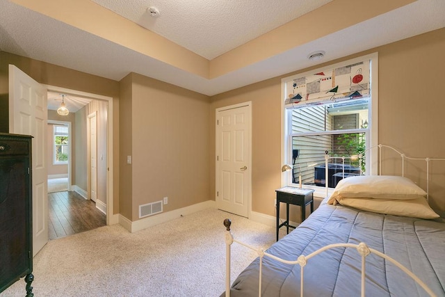 carpeted bedroom featuring visible vents, a textured ceiling, and baseboards