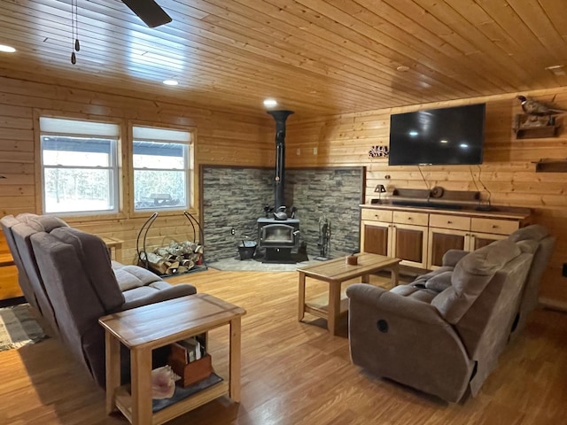 living room with wooden ceiling, wooden walls, light wood-style floors, and a wood stove