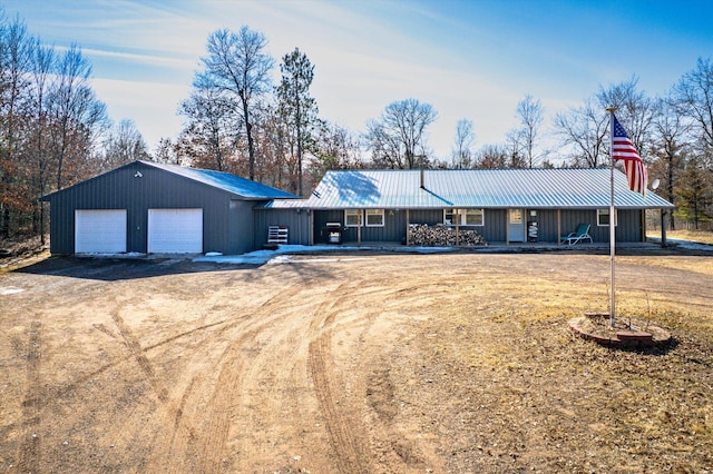 ranch-style home featuring an attached garage, driveway, metal roof, and a standing seam roof