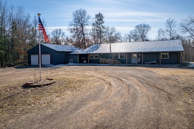 single story home with a garage, dirt driveway, and metal roof