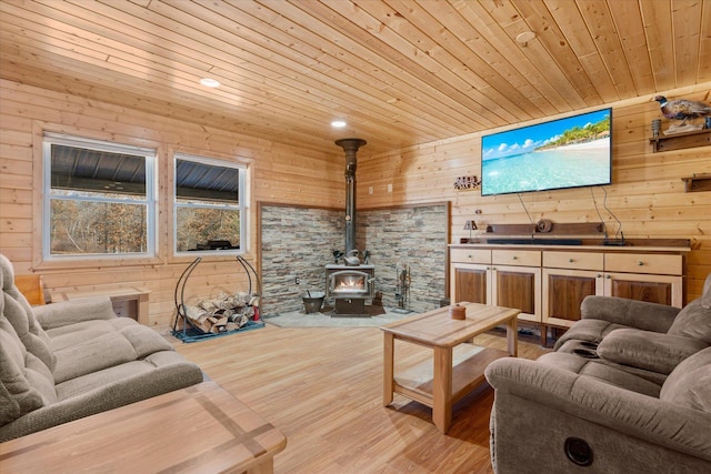 living area featuring wooden walls, wooden ceiling, a wood stove, and wood finished floors