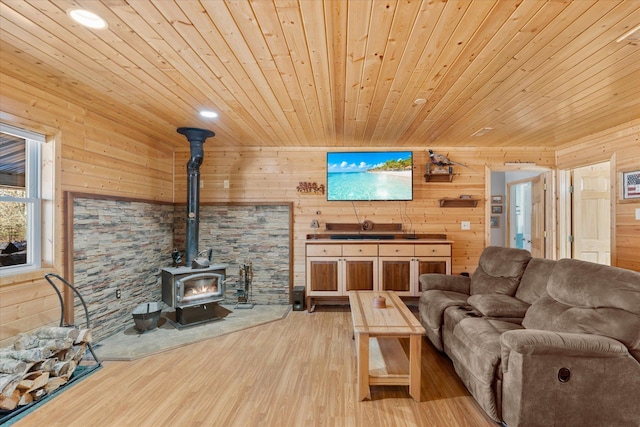 living area with wooden walls, wooden ceiling, light wood-type flooring, and a wood stove