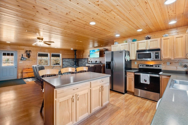 kitchen with light brown cabinets, wood ceiling, a kitchen bar, light wood-style flooring, and stainless steel appliances