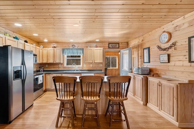 kitchen featuring a sink, light brown cabinetry, stainless steel appliances, a kitchen breakfast bar, and light wood-type flooring