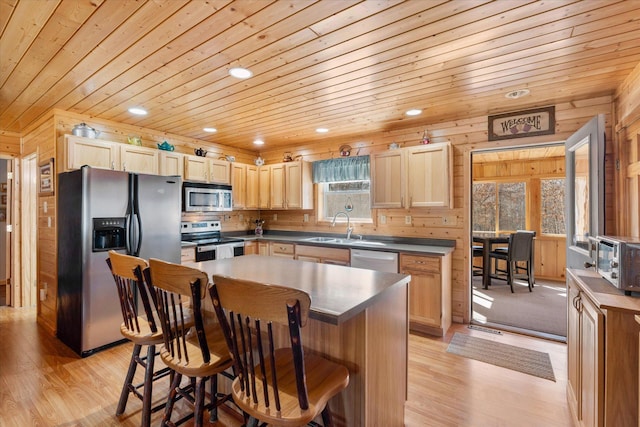 kitchen featuring light brown cabinets, dark countertops, stainless steel appliances, wooden ceiling, and a breakfast bar area