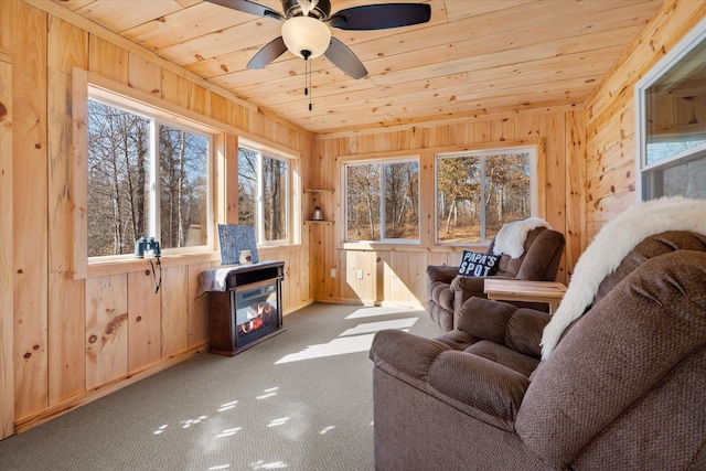 interior space featuring ceiling fan, wooden ceiling, carpet flooring, and wood walls