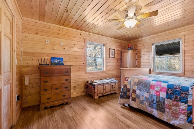 bedroom featuring multiple windows, wooden walls, wooden ceiling, and light wood finished floors