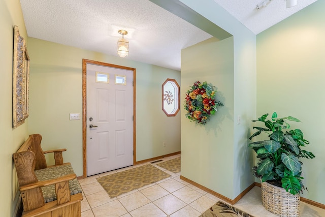 foyer with baseboards, a textured ceiling, and light tile patterned flooring