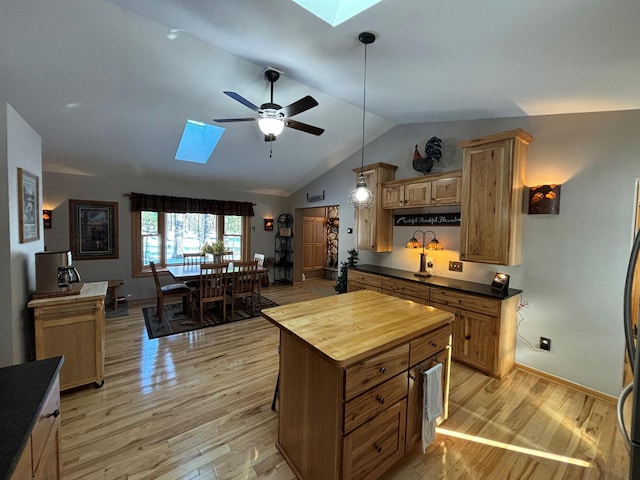 kitchen with butcher block counters, lofted ceiling with skylight, a ceiling fan, and light wood-style floors