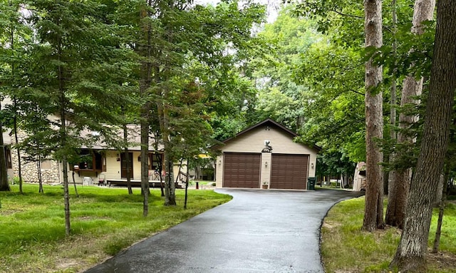 view of front of home featuring a garage, an outbuilding, and a front lawn