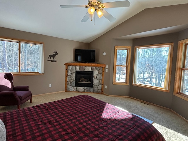 carpeted bedroom with visible vents, baseboards, a ceiling fan, lofted ceiling, and a stone fireplace