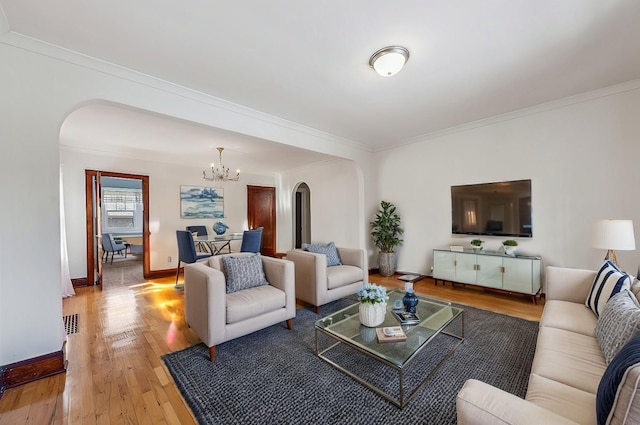 living room with arched walkways, a chandelier, baseboards, light wood finished floors, and crown molding