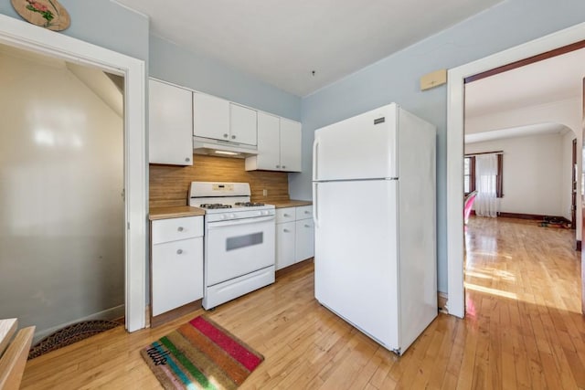 kitchen with white appliances, under cabinet range hood, decorative backsplash, and light wood finished floors