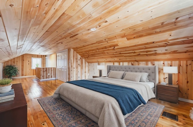 bedroom with visible vents, vaulted ceiling, wood walls, wooden ceiling, and hardwood / wood-style floors