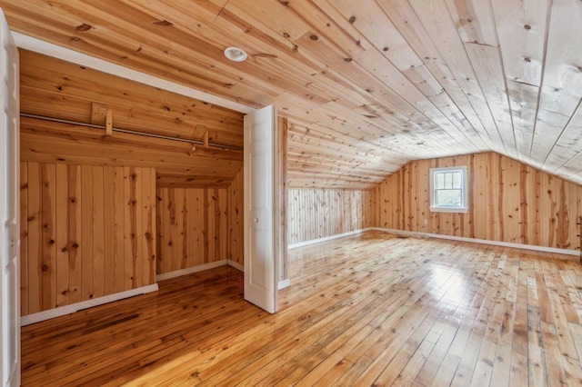 additional living space with wood ceiling, wooden walls, vaulted ceiling, and hardwood / wood-style floors