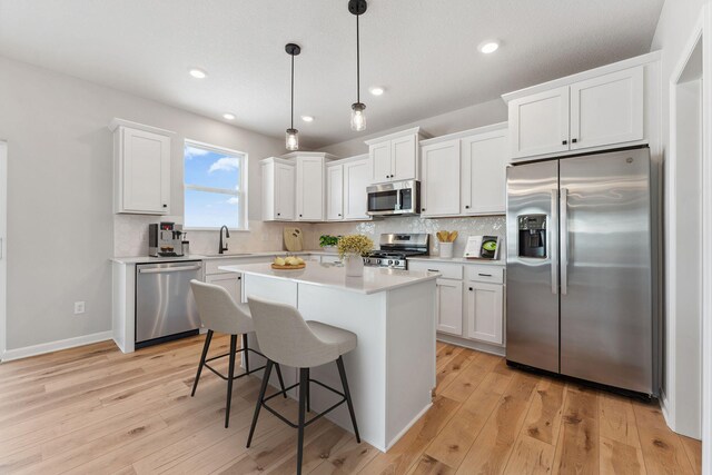 kitchen with a sink, decorative backsplash, appliances with stainless steel finishes, and light wood-style floors