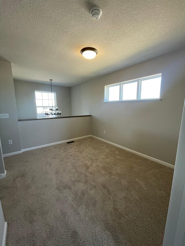 empty room featuring visible vents, baseboards, carpet flooring, and a chandelier