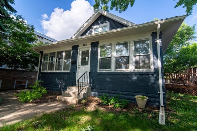 bungalow-style home featuring entry steps, brick siding, and a wooden deck