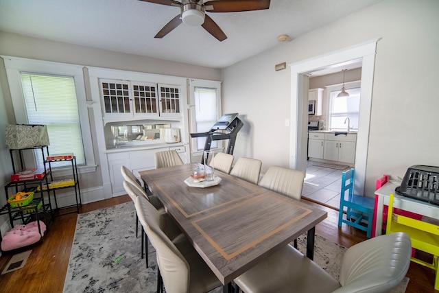 dining space with wood finished floors, visible vents, and a ceiling fan