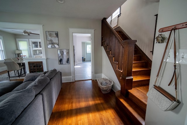 living area featuring baseboards, stairway, and wood finished floors